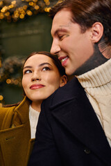 Young pair radiates happiness as they enjoy a warm, intimate moment surrounded by holiday lights