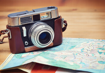 Travel, map and photography with camera on table for itinerary schedule, adventure explore and direction. Holiday, vintage and trip with vacation planning for tourism, navigation and discovery