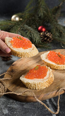 A sandwich with red caviar in hand against a festive New Year’s background.