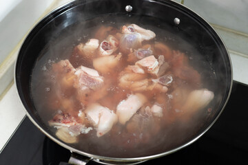 The pork trotters are blanched in a pot