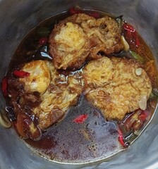 fried eggs in sweet spicy sauce with chopped red chilies