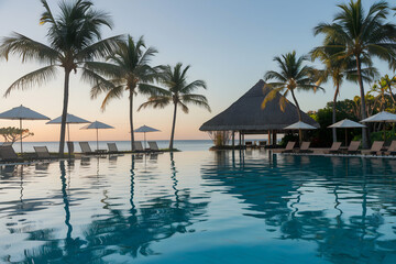 Fototapeta premium Resort pool reflecting skies, framed by loungers, umbrellas, and palm trees