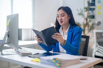 Fototapeta premium A woman is sitting at a desk reading a book