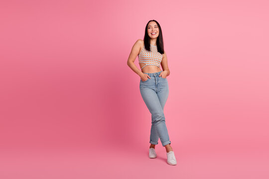 Charming young woman in trendy summer outfit poses against pink background exuding confidence and joy