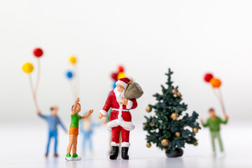 Miniature Santa Claus holding a gift surrounded by children and colorful balloons