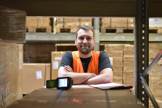 portrait of friendly warehouse worker in a forwarding agency - interior with forklift - transport and storage of goods