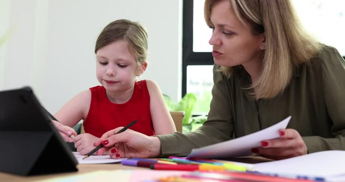 Concentrated mother corrects mistakes of daughter in text. Woman explains importance of punctuation to inquisitive schoolgirl slow motion