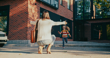 View from behind of loving mother kneeling down and making open arms gesture. Kid running towards...