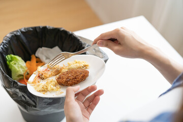 Compost from leftover food, refuse asian young housekeeper woman, girl hand using fork scraping waste from dish, throwing away putting into garbage, trash or bin..Environmentally responsible, ecology.