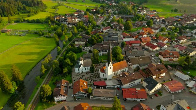 St. Verena in Fischen im Allgaeu, Bavaria, Germany is charming Alpine village. Seen from above, it offers breathtaking aerial views of historic church and countryside aerial view at sunset in summer. 