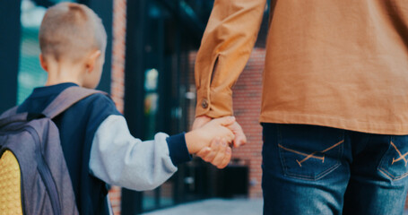 View from behind of small Caucasian boy walking together with his caring dad. Protective father...
