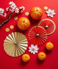 Obraz premium egant Chinese New Year decorations feature tangerines, cherry blossoms, gold coins, and paper fans on a vibrant red background arranged artfully.