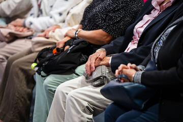 hands and handbags of elderly women sitting in a row