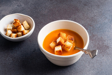 Butternut squash soup with bread croutons in  ceramic bowl