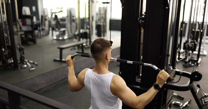 Professional sportsman maintains steady rhythm as pushes and pulls handles of training machine. Athlete concentrates on building biceps slow motion