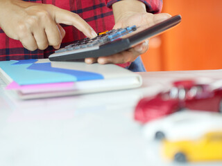 Hand pressing calculator with car on desk. Car insurance and finance business concept.Copy space.