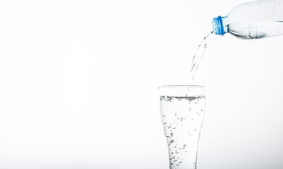 Pour drinking water into a glass isolated on white background,Pouring water from bottle into glass on blue background