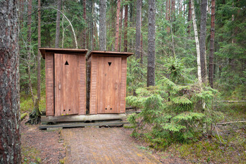 Two identical wooden facilities in the forest on the trail