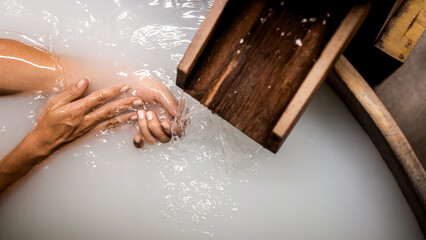 Close-up of a woman's hands touching powdery white water in a Japanese bath. A serene spa moment, perfect for relaxation, wellness, and peaceful retreat concepts.