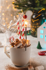 A sparkler is burning in a mug with marshmallows and cocoa