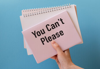 A woman holds a poster with an inscription and a slogan You Can't Please on blue background.