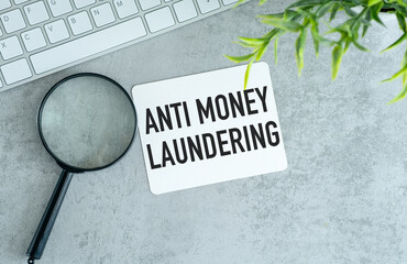 Anti-money laundering AML . text on white paper and white sticker on gray table.