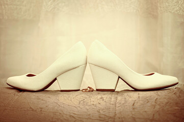 Bride's high heel shoes on sofa. beige wedding shoes on the sofa with wedding rings in the middle.