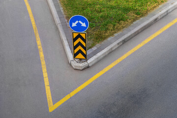 A road fork with road signs: warning blue and orange-black stripes and yellow solid lines...