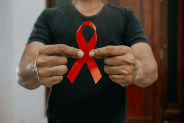 Man holding red ribbon. AIDS prevention campaign. December red, blood donation.