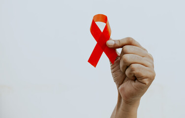 Hand holding Red Ribbon for December World Aids Day (acquired immune deficiency syndrome), multiple...