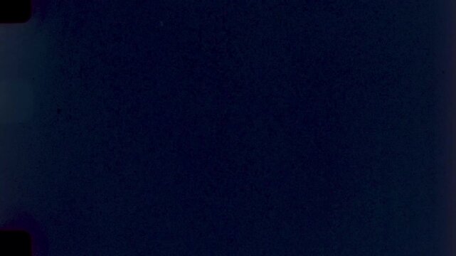 Midnight Blue Film Grain Texture,High-resolution scan of a 35mm film frame with deep blue tones and sprocket holes for creative projects.
