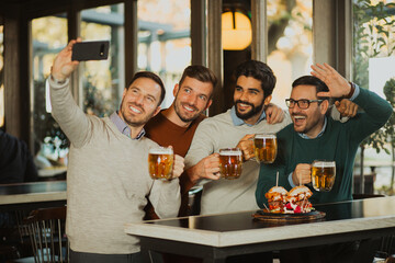Group of friends drinking beer in a pub, taking selfie