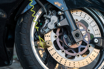 A motorcycle wheel with a lock attached to its disc brake.