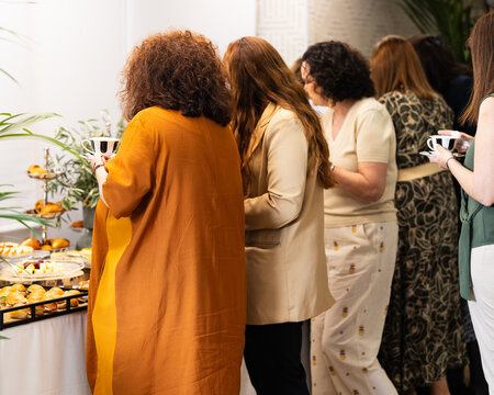 Coworkers at an office event picking up food from a banquet table