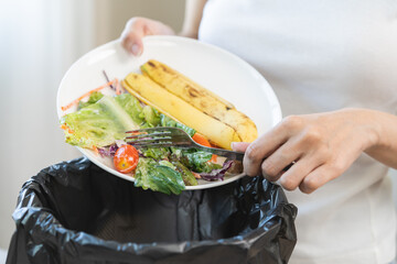 Compost from leftover food asian young housekeeper woman hand holding salad plate use fork scraping...