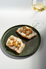 Delicious open-faced sandwich with cream cheese and mussels served on a green plate and glass of wine