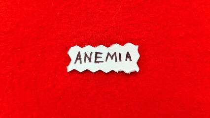 Anemia word letters text handwritten calligraphy design on white paper label note isolated on a red background surface with copy space. Closeup macro top view. Anemia creative concept