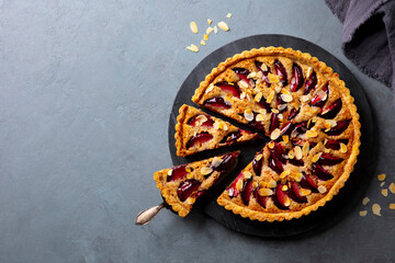 Plum pie on a marble cutting board. Grey background. Copy space. Top view.