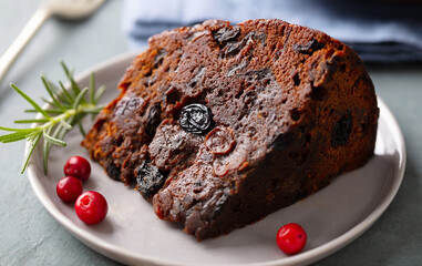 Christmas fruit cake, pudding on white plate. Close up. Grey background. Close up.