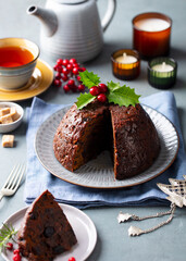 Christmas pudding, fruit cake with cup of tea. Traditional festive dessert. Grey background.