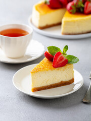 Cheesecake dessert with fresh strawberries and cup of tea. Grey background. Close up.