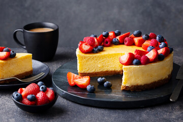 Cheesecake dessert on a marble cutting board with cup of coffee. Grey background. Close up.