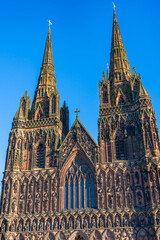 Fototapeta premium The western spires above the entrance of Lichfield Cathedral with a beautiful blue sky
