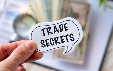 Businessman holding a card with text trade secret .Keyboard, diagram and white background