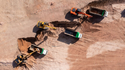Aerial view road motor grader flatting dirt road surface, Motor grader road construction grader industrial machine construction site new road, Aerial view group excavator working on construction site.