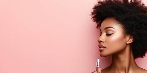 A beautiful woman with radiant skin and afro hair holds a small serum bottle against a soft pink background, exemplifying elegance, skincare, and natural beauty.