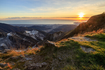 A breathtaking sunset over the Carrara marble quarries, with the Mediterranean Sea and the city of Carrara in the distance.