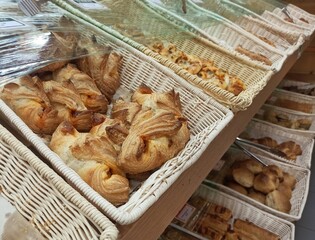 A closeup picture of various bakery items stacked in a jute basket at a bakery