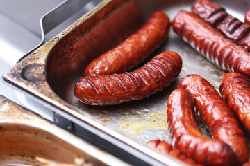 Fried sausages in buffet trays. Hot food served in hotel warmers. Delicious meat snack for...