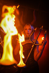 A beautiful woman with devilish horns on a red blood like smoky hell concept background.